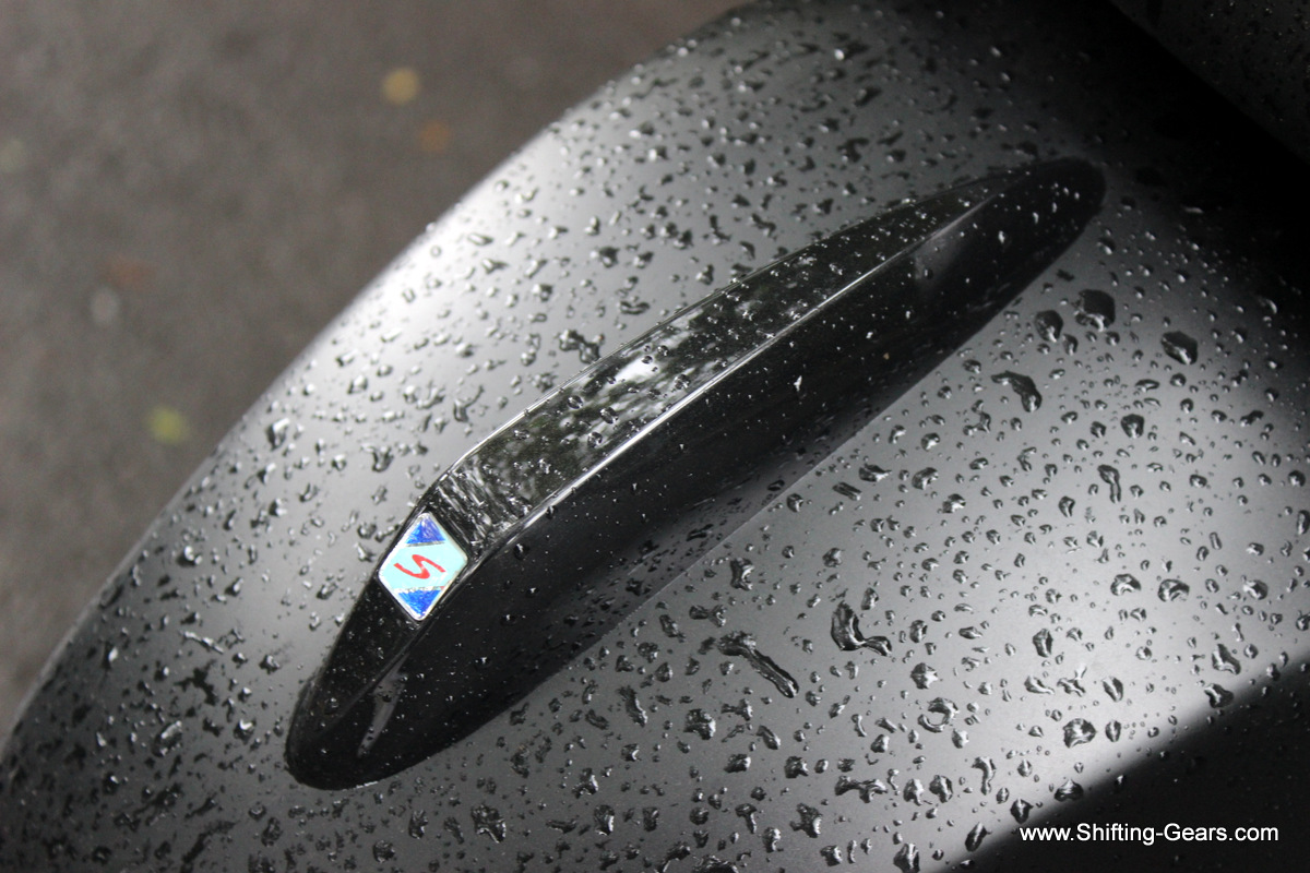 S badge on a gloss black ornament on the front fender
